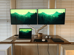 一张工作桌，上面有一台笔记本电脑和两台显示器。